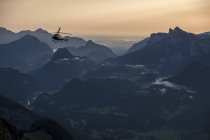 Áustria, Estado de Salzburgo, Loferer Steinberge, helicóptero na paisagem montanhosa no crepúsculo — Fotografia de Stock