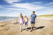Netherlands, Zandvoort, happy family walking on the beach — Stock Photo