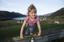 Österreich, Tirol, Walchsee, glückliches Mädchen auf der Bank — Stockfoto