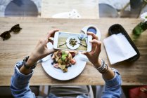 Overhead view of woman taking smartphone picture of pancakes in cafe — Stock Photo