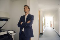 Gelangweilter Geschäftsmann lehnt an Wand neben Kopiergerät — Stockfoto