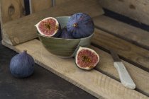 Sliced and whole fresh figs, kitchen knife and wooden box — Stock Photo
