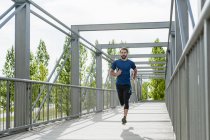 Man running on a bridge — Stock Photo