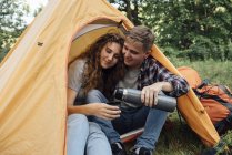 Jeune couple assis dans la tente dans la nature et boire du thé — Photo de stock