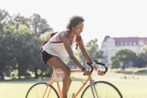Joven sonriente montando bicicleta en el parque de verano - foto de stock