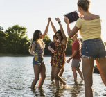 Gruppo di amici felici con tablet in un fiume al tramonto — Foto stock