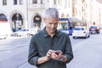 Reifer Mann benutzt Handy in der Stadt — Stockfoto