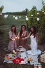 Friends having a picnic in a vinyard, burning sparklers — Stock Photo