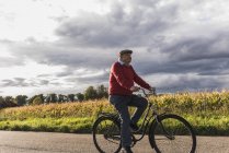 Uomo anziano in bicicletta sulla strada di campagna — Foto stock