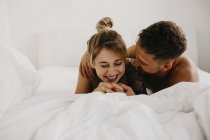 Romántico feliz joven pareja acostada en la cama - foto de stock