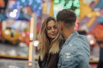 Jeune couple amoureux, embrasser à une fête foraine — Photo de stock