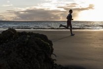 Jogger correre sulla spiaggia al tramonto — Foto stock