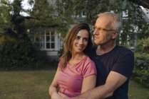 Smiling mature couple in garden of house — Stock Photo