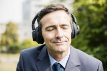 Бізнесмен із закритими очима слухає музику з навушниками — стокове фото