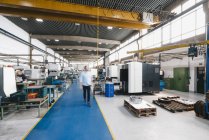 Uomo d'affari a piedi attraverso officina di fabbrica — Foto stock
