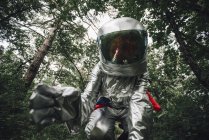 Close-up of spaceman examining plants in forest — Stock Photo