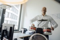 Empresário tocando bateria no escritório — Fotografia de Stock