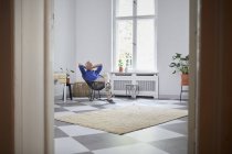 Entspannter älterer Mann sitzt zu Hause und lächelt — Stockfoto