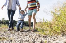Happy boy with parents walking at riverside on sunny summer day — Stock Photo
