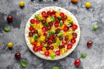 Unbaked pizza with tomatoes and basil leaves — Stock Photo