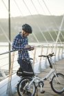 Giovane con bicicletta pieghevole sul ponte utilizzando tablet — Foto stock