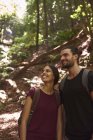 Усміхнена пара стоїть в лісі і озирається навколо — стокове фото