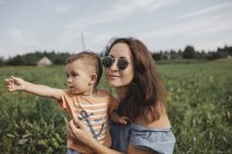 Mãe com bebê em um campo olhando para a distância — Fotografia de Stock