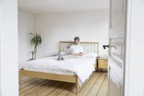 Зріла людина розслабляючий з ноутбуком в ліжку — стокове фото