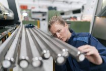 Junge Frau arbeitet in High-Tech-Firma und überprüft Stahlstäbe — Stockfoto