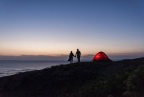 Романтическая пара, кемпинг на пляже, прогулка в сумерках, держась за руки — стоковое фото