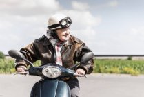Uomo anziano attivo eccesso di velocità su scooter a motore su strada di campagna — Foto stock