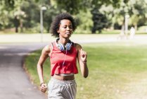 Joven mujer positiva corriendo en el parque de verano - foto de stock