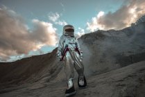 Spaceman exploring nameless planet, walking in dust cloud — Stock Photo