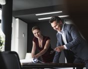 Lächelnde Geschäftsfrau und Geschäftsmann im Büro besprechen Plan auf Schreibtisch — Stockfoto