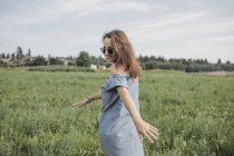 Mujer sonriente con gafas de sol caminando en el campo rural - foto de stock