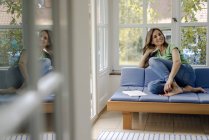 Porträt einer lächelnden reifen Frau, die zu Hause auf der Couch sitzt — Stockfoto