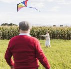 Senior couple flying kite in rural landscape — Stock Photo