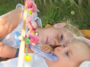 Freckled girl lying with baby girl on blanket on a meadow — Stock Photo