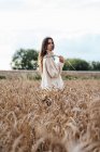 Young woman wearing oversized turtleneck pullover standing in corn field — Stock Photo