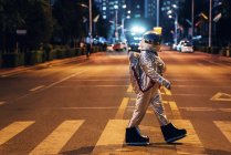 Spaceman walking on a street in city at night — Stock Photo