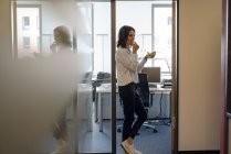 Businesswoman standing in office at door and eating grapes — Stock Photo