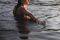 Giovane donna che tocca la superficie dell'acqua in un lago — Foto stock