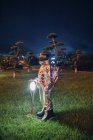 Космонавт, стоящий у лампы в парке ночью — стоковое фото