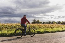 Hombre mayor montar en bicicleta en el carril del país - foto de stock