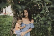 Ritratto di madre che tiene il bambino in giardino — Foto stock