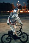 Spaceman in città di notte sul parcheggio in sella alla bici bmx — Foto stock