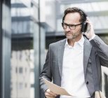 Portrait of businessman with documents and headphones — Stock Photo
