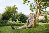 Mature man standing in garden wearing apron — Stock Photo