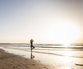 Молода жінка заняттях йогою на піщаному пляжі — стокове фото
