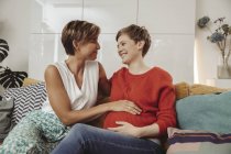 Joyeux couple lesbien touchant le ventre de la future mère — Photo de stock